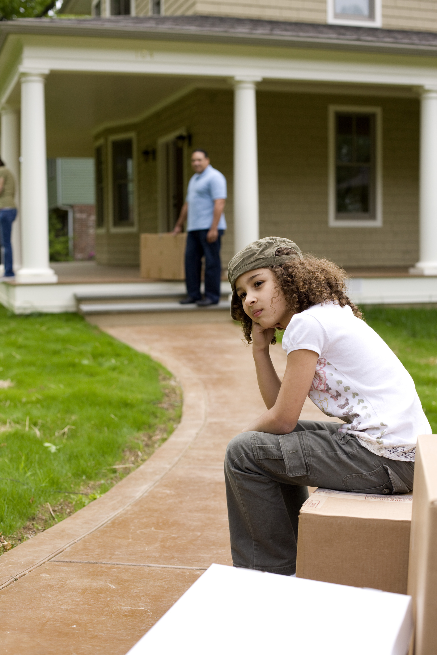 Upset girl sitting on moving boxes outside house
