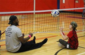An adult mentor and youth practice sitting volleyball at the 2017 Playmakers Program. 